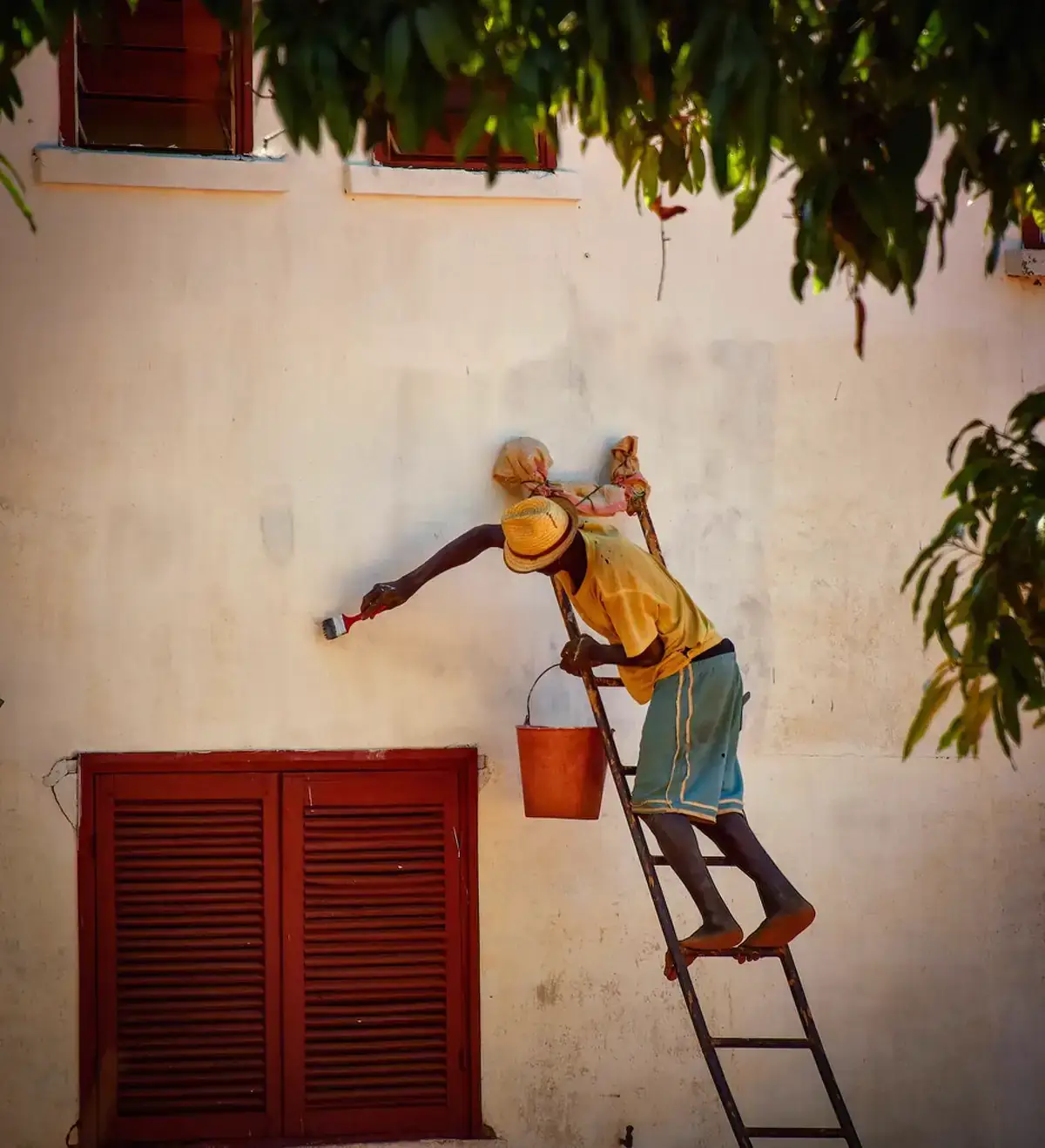 House painter applying fresh paint to exterior siding with a brush