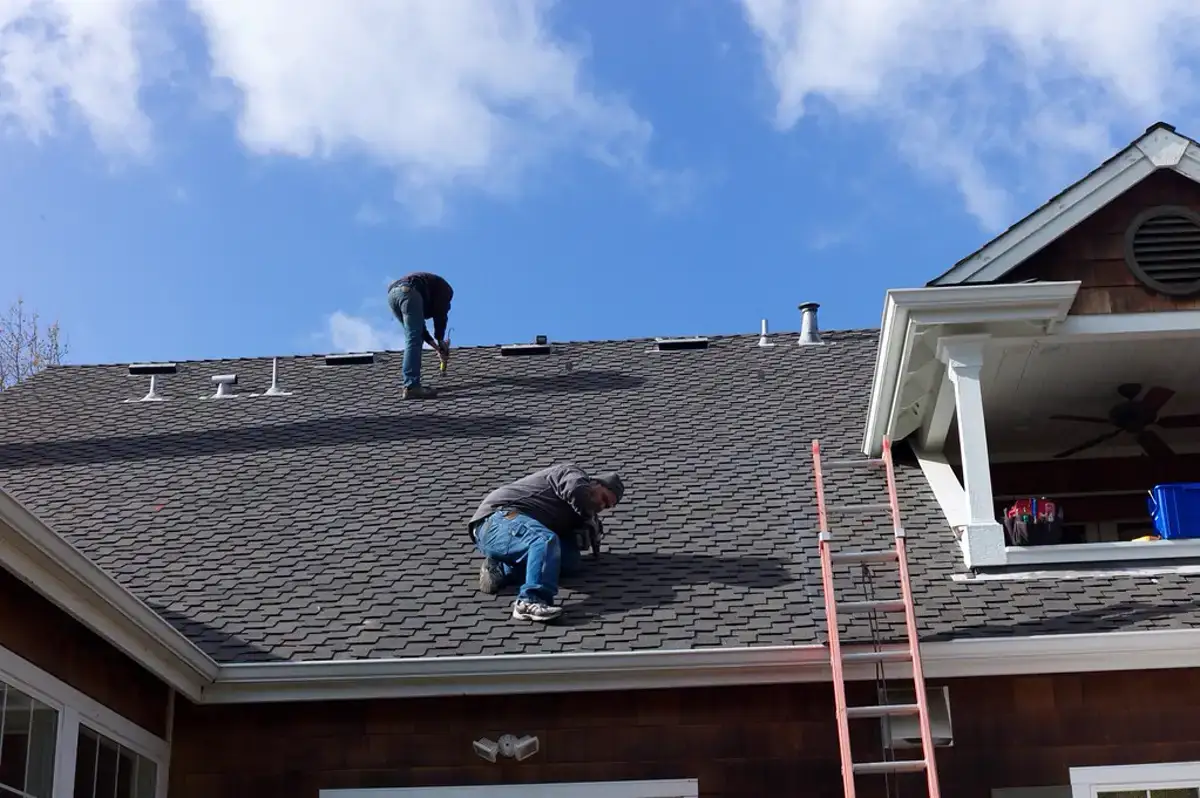 Roofing crew installing asphalt shingles on a residential roof