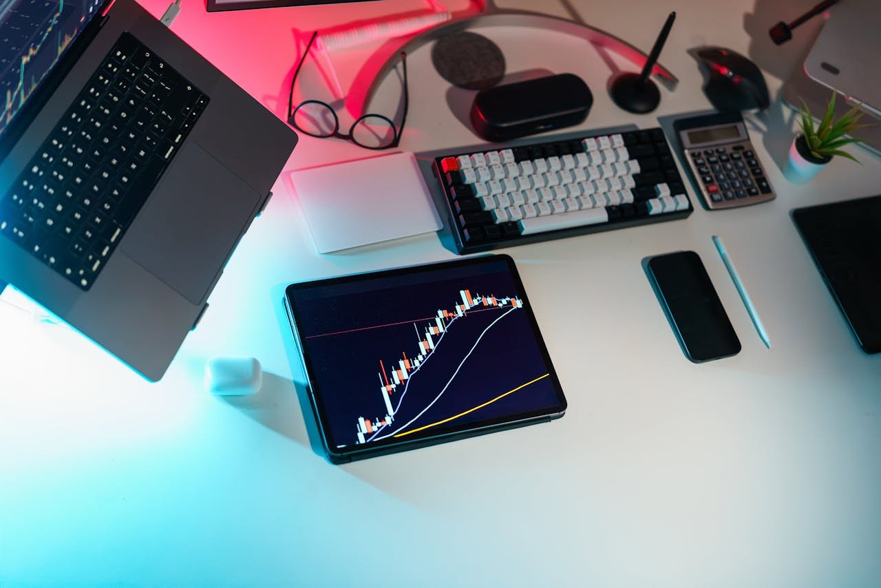 A modern desk setup featuring financial analytics on digital devices in an office setting.