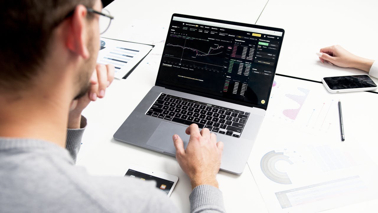 Business professional analyzing stock market data on a laptop for investment insights.